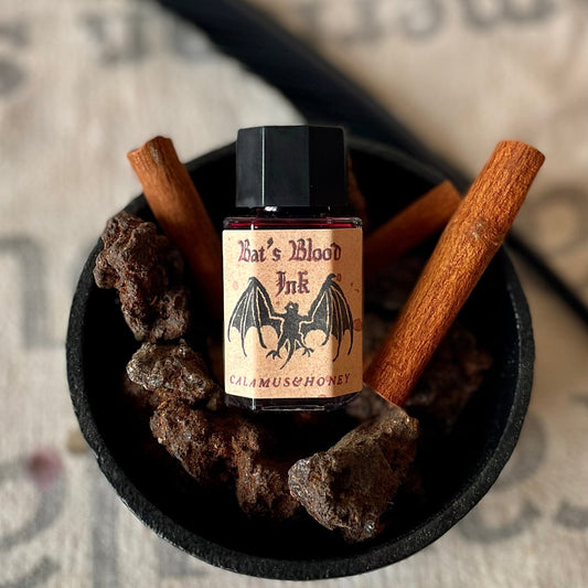 Bottle of 'Bat's Blood Ink' with ingredients on a textured surface